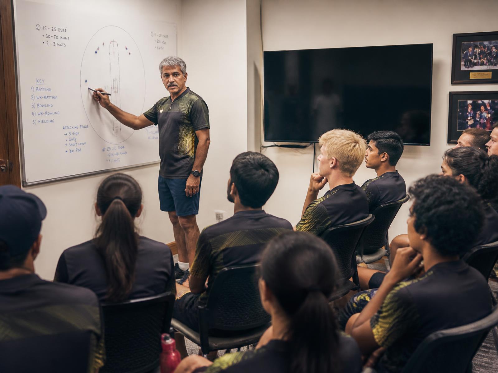 Coach drawing field placements on a whiteboard for a mixed squad